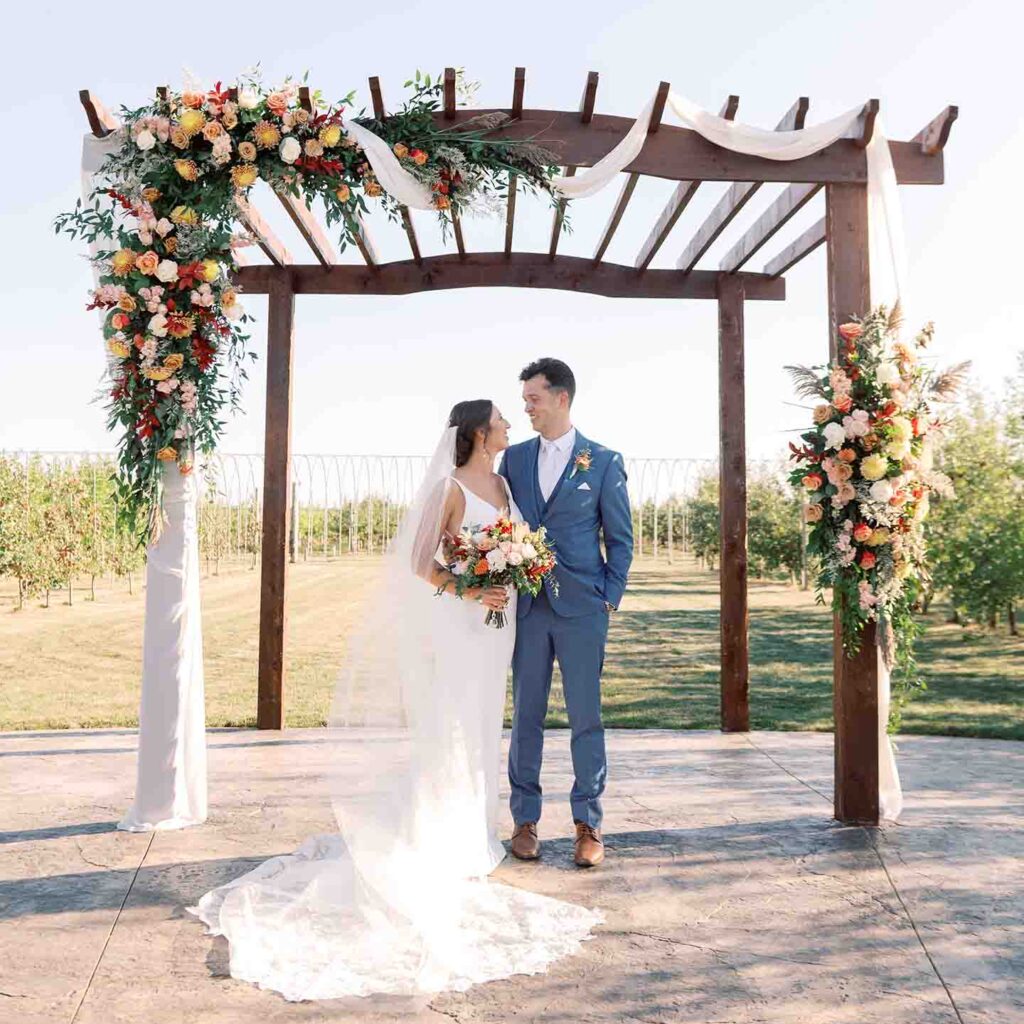 bride and groom under floral accented arbor for an outdoor wedding by Lovejoy Events